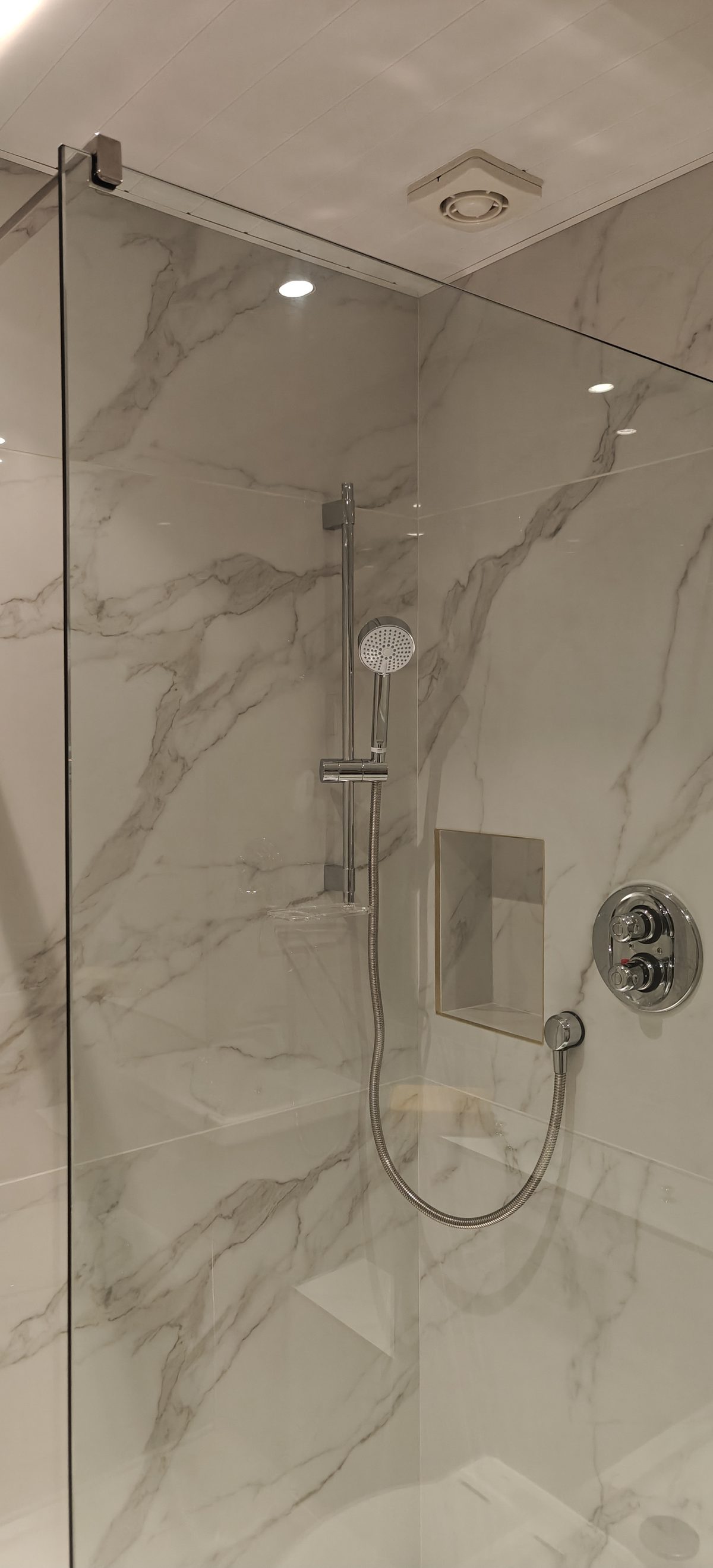 Shower enclosure with marble effect tiles and chrome fittings