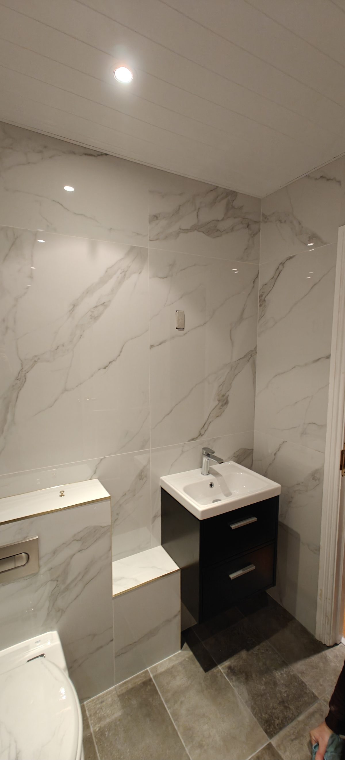 White marble ensuite with glass shower screen and dark vanity