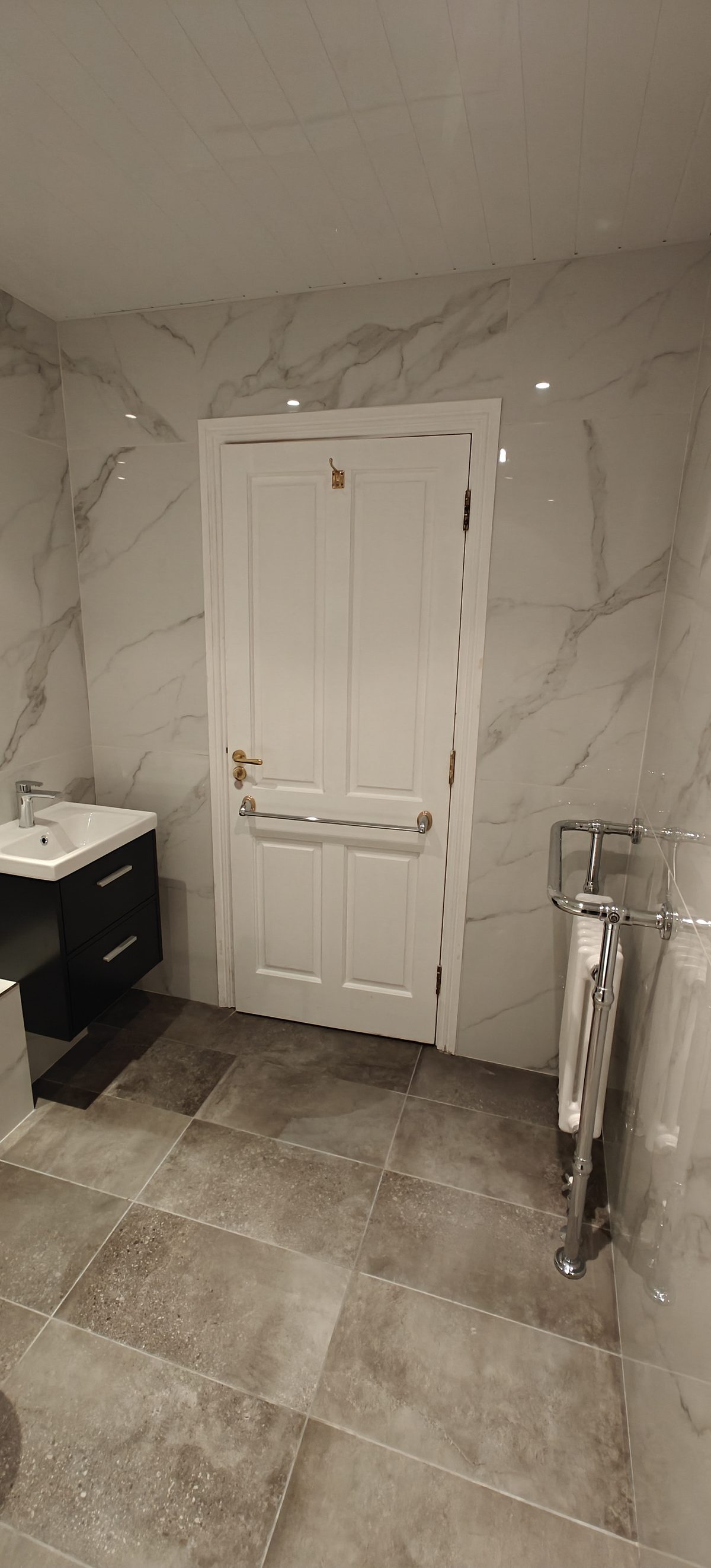 Marble effect bathroom with white panelled door and grey stone floor