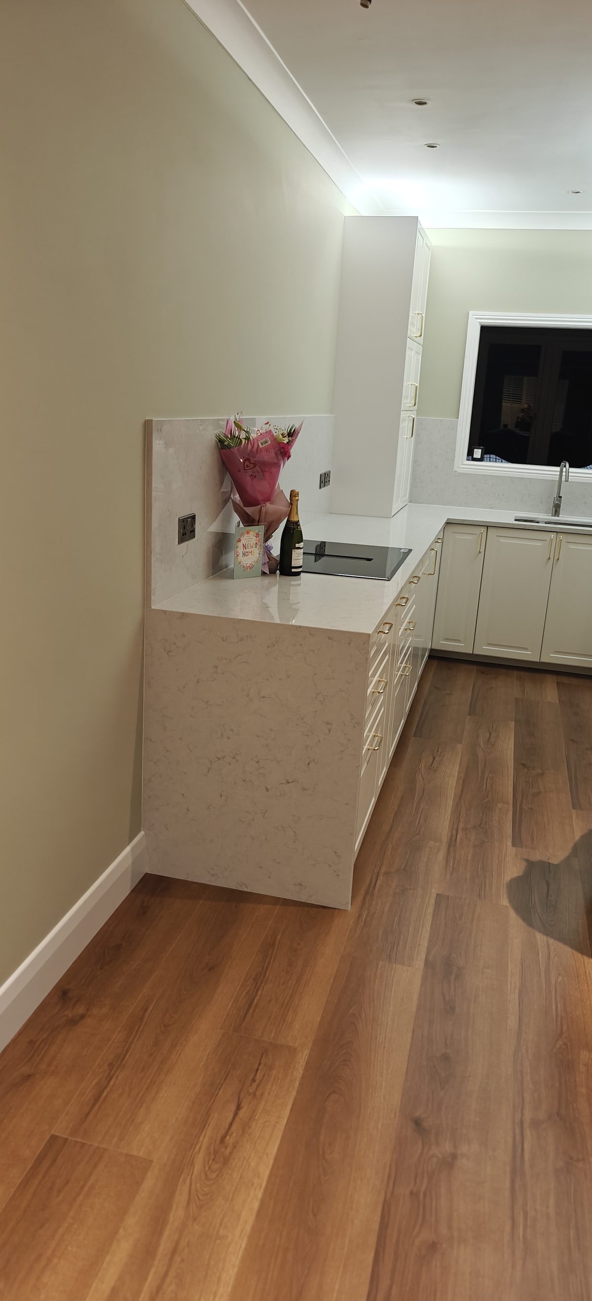 Cream shaker kitchen with oak flooring and a long run of units